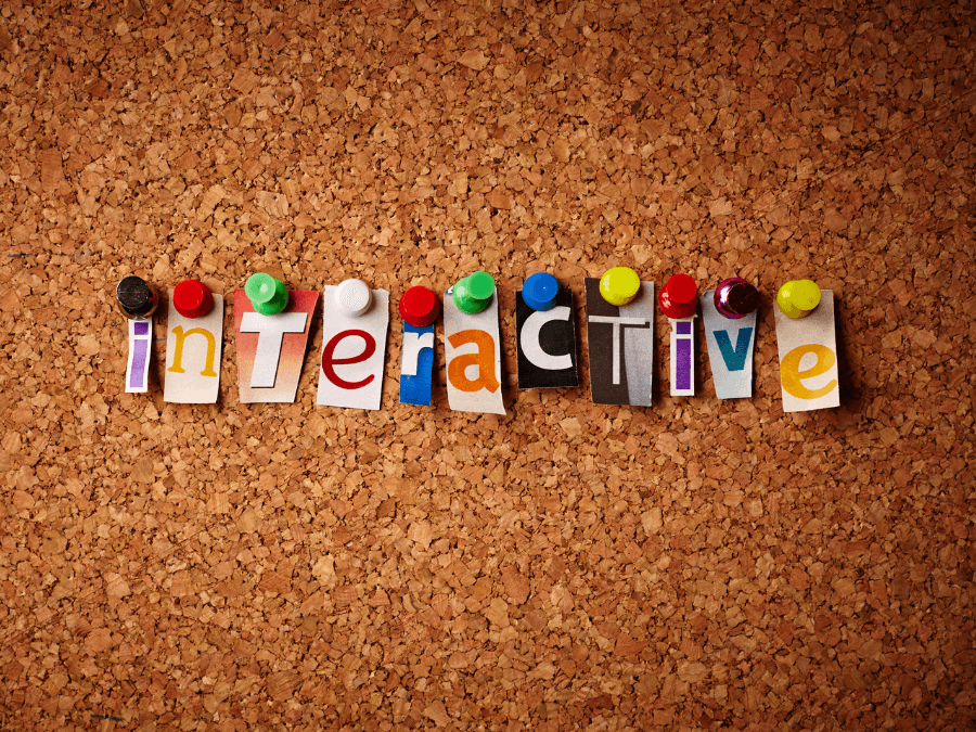 The word interactive spelled out in cut-out letters pinned to a cork board.